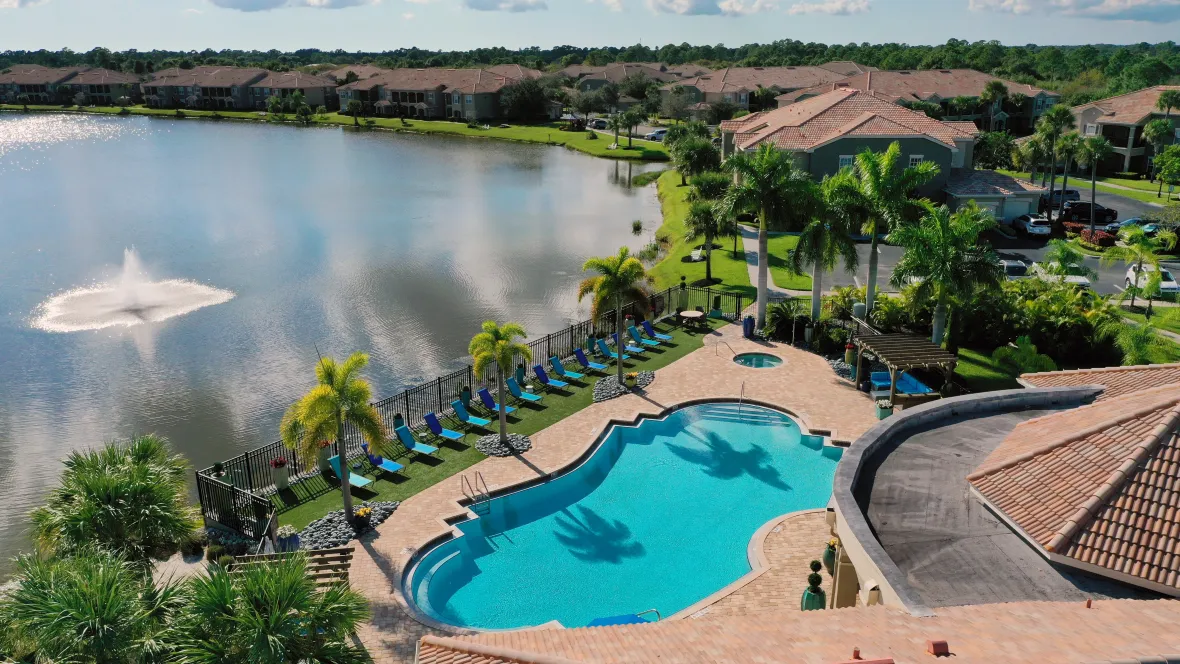 A drone shot above the sparkling pool, designer sun deck, lake, and tranquil fountain – capturing elegance and luxury from above.