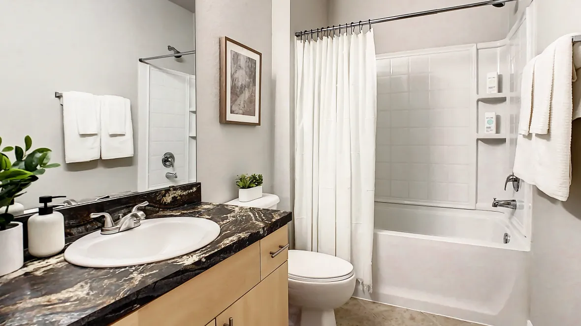 Bright bathroom with shower/tub combo, large vanity, and exceptional storage space.