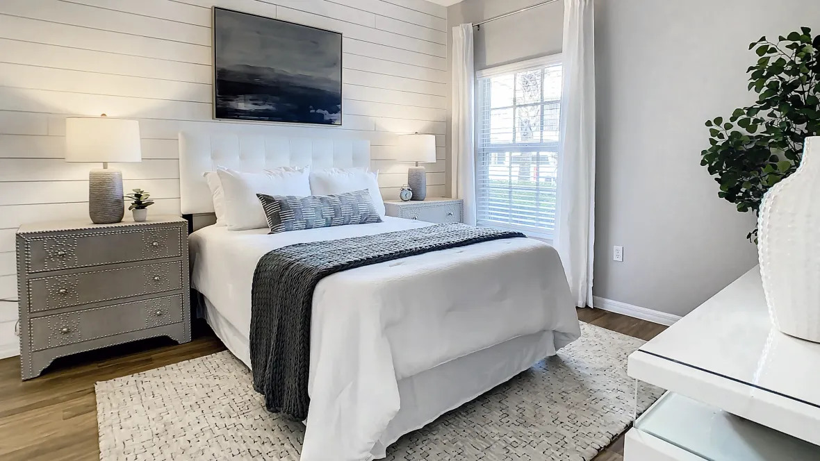 Immaculate bedroom with bright window with privacy blinds, a modern ceiling fan, and soothing decor.