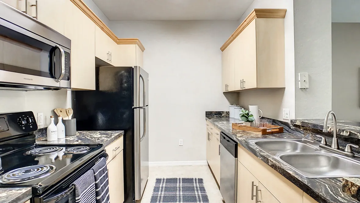 A look down the length of the galley-style kitchen adorned with a new appliance package including the coveted dishwasher and microwave over the stovetop for ultimate counter saving convenience.