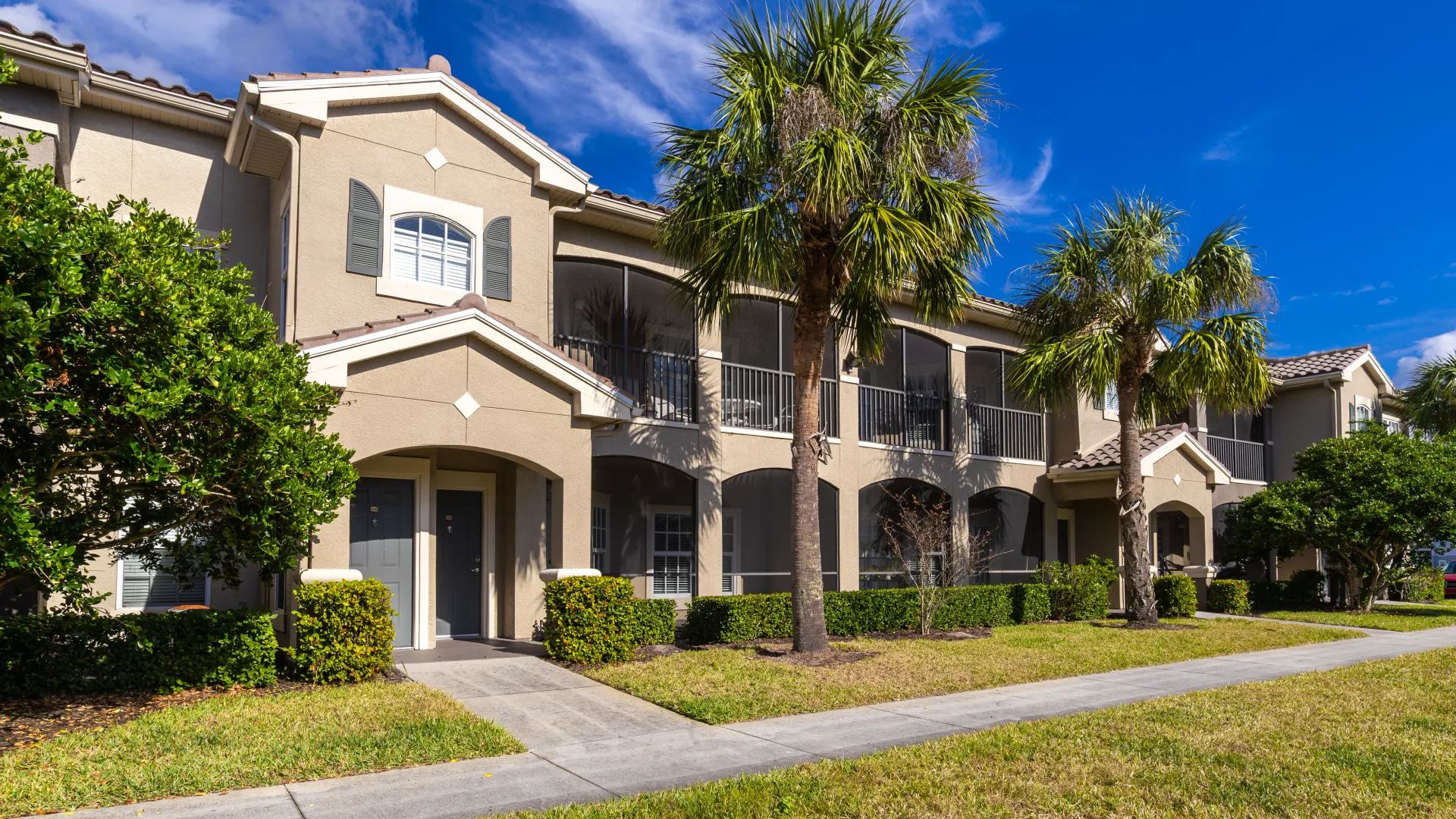 Mediterranean-style apartment buildings with stucco exteriors, arched entryways, and lush landscaping.