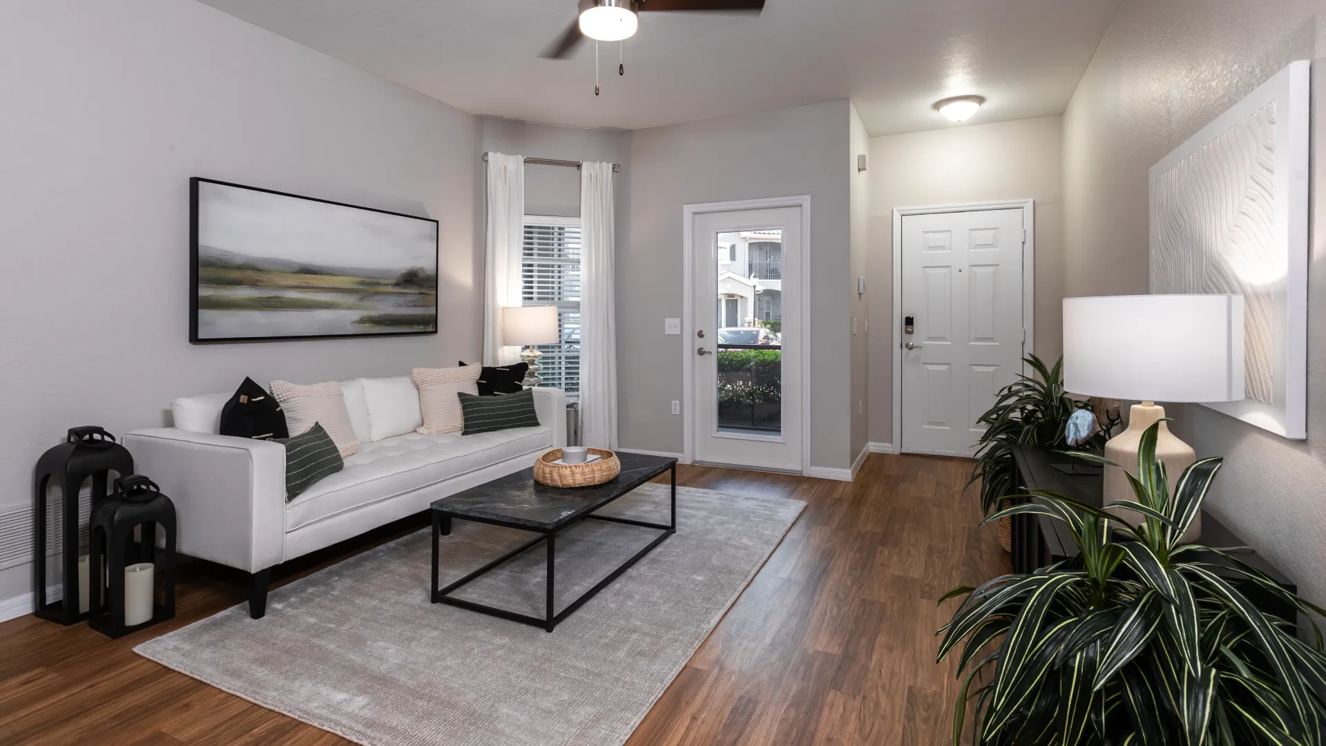 Contemporary living room with a white sofa, modern decor, a sleek coffee table, and wood flooring.