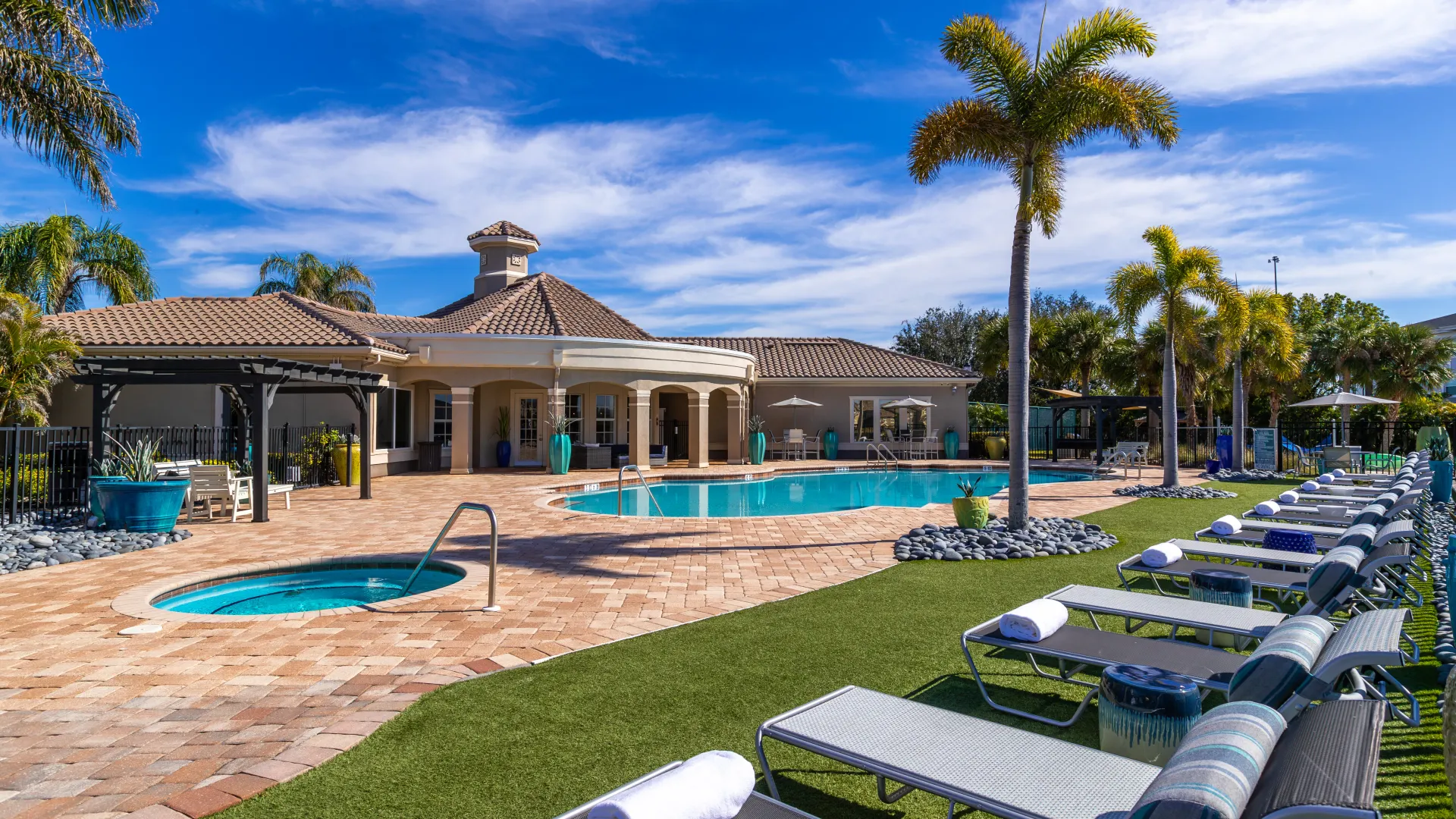 Sunlit pool deck featuring lounge chairs, lush greenery, and a beautifully designed outdoor retreat.