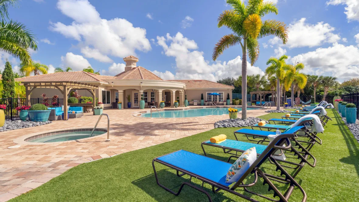 A row of vibrant blue pool loungers on the pool deck with faux grass underneath inviting a luxurious experience around the pool.