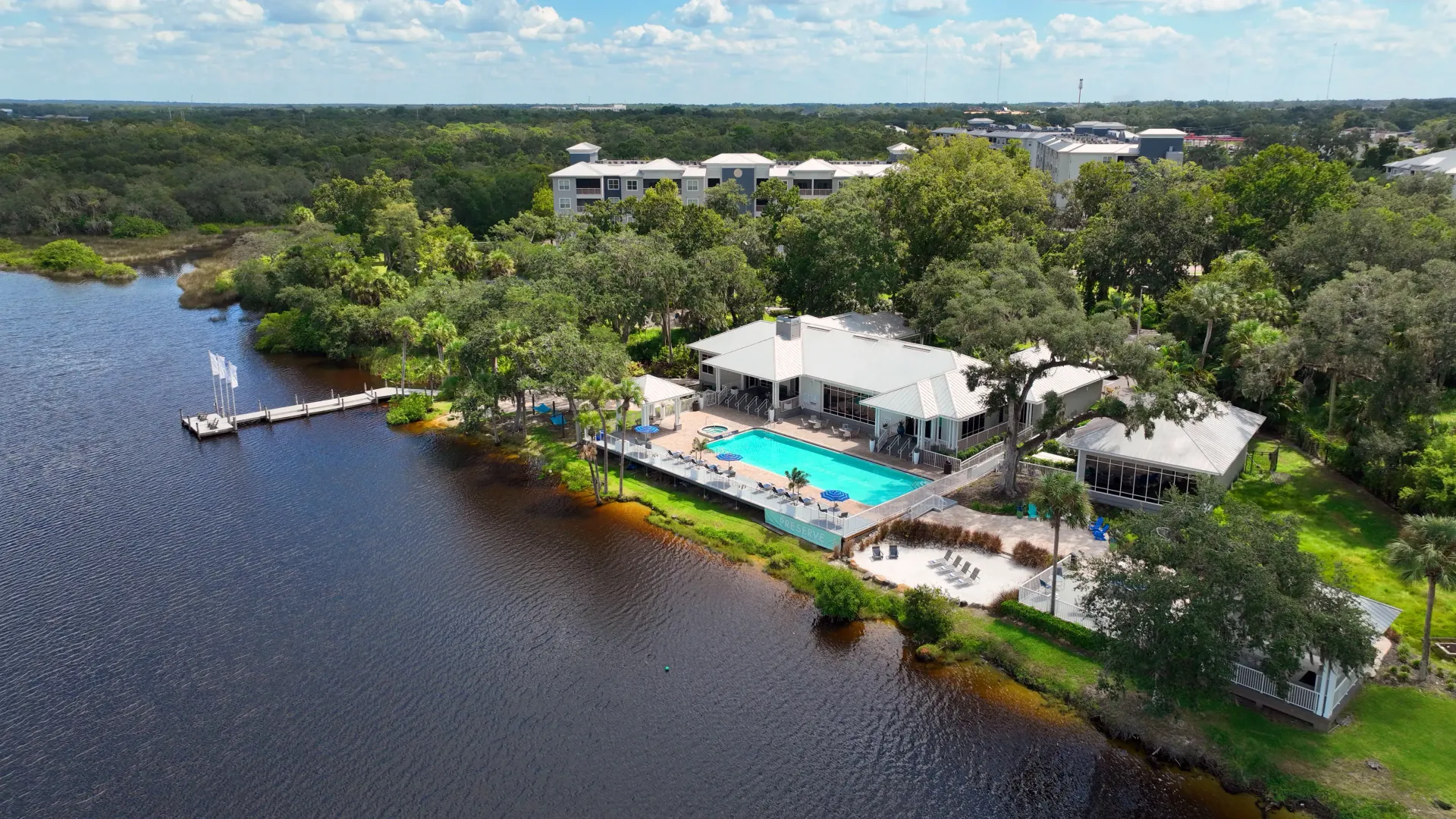 A drone shot capturing the riverside community, showcasing a shimmering pool, clubhouse, fitness center, and all the incredible outdoor amenities surrounded by natural landscapes and endless outdoor adventures.