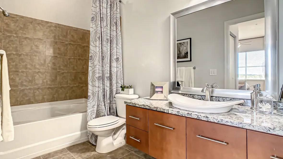 A capacious master bathroom with an oversized garden tub, ample granite countertop space, and abundant storage drawers and cabinet space, complemented by a fancy modern sink bowl.
