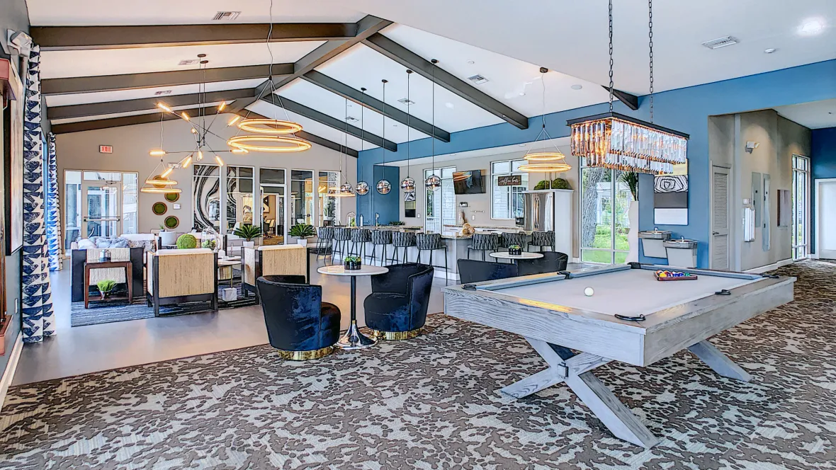 A majestic clubhouse wows with tall ceilings with wood beam detailing and captivating contemporary chandeliers with amenities for residents to enjoy – complete with designer carpets, velvety plush chairs, and bar-style seating at the full kitchen.