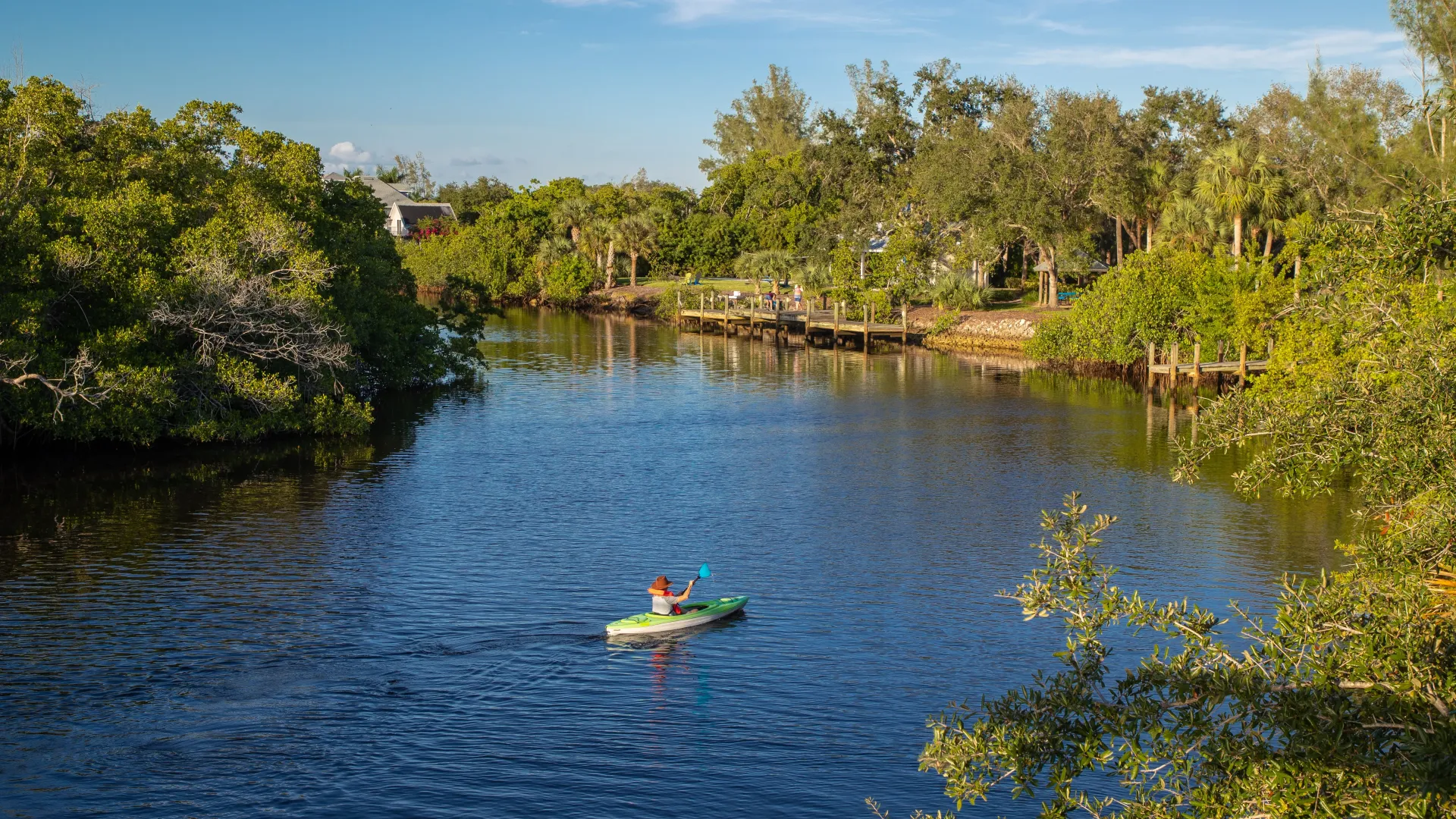 A resident paddling down the river exploring the serene Alafia River enveloped by sweeping trees on both shores.