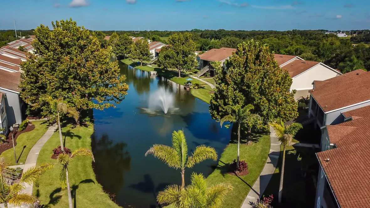 A captivating aerial view showcasing the Soleil Blu community, featuring the mesmerizing lake fountain, lush landscaping, and serene lakeside setting.