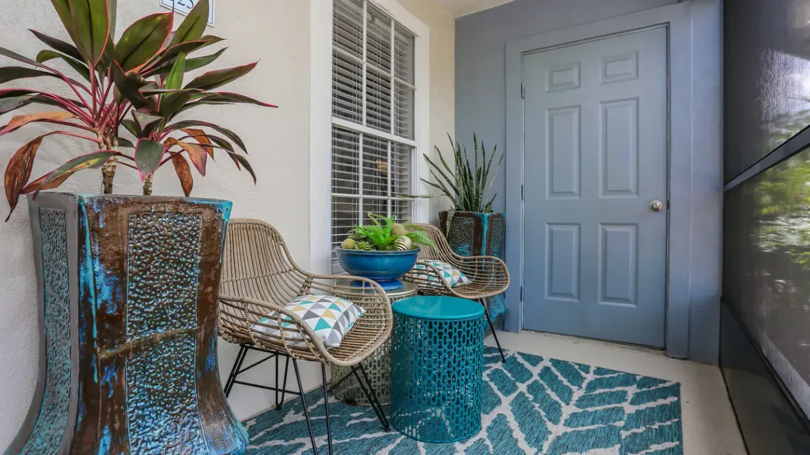 A charming screened-in patio, a perfect nook for outdoor seating and lush plant arrangements with a secure door to a storage closet.