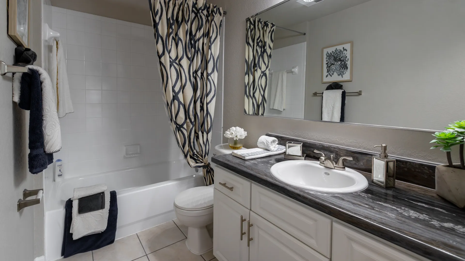 A sleek, modern bathroom adorned with spacious white cabinetry, an extended vanity, and a refined white-tiled shower, creating a polished ambiance.