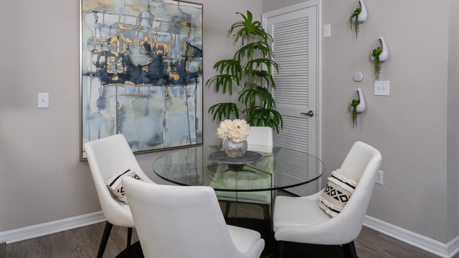 A dining room with dining table and four chairs, with brush-nickel chandelier overhead for an elegant dining space.