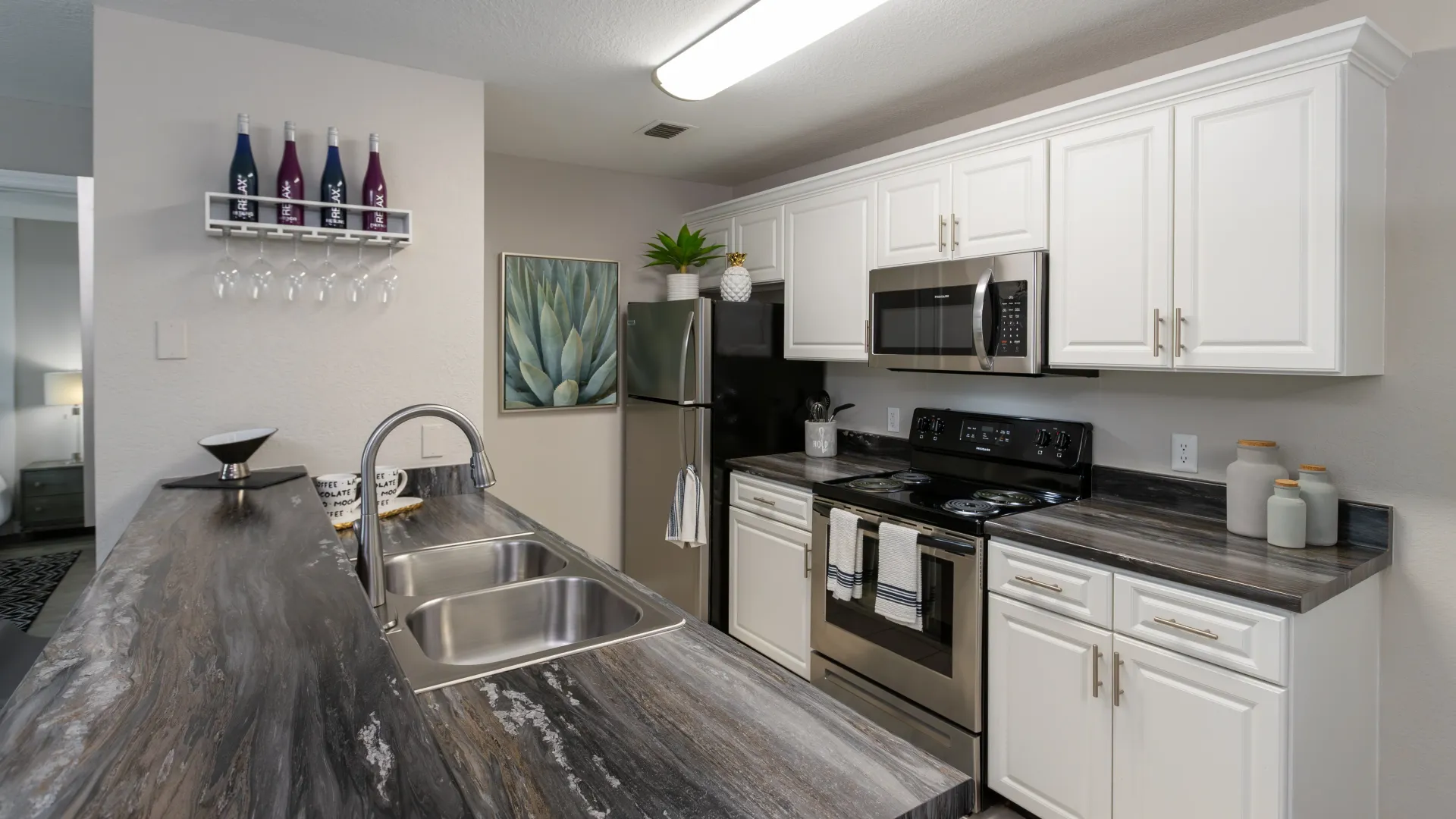 Modern kitchen with stainless steel appliances, custom white cabinetry, and sleek countertops at Soleil Blu Apartments in St Cloud, FL, offering stylish and functional space.