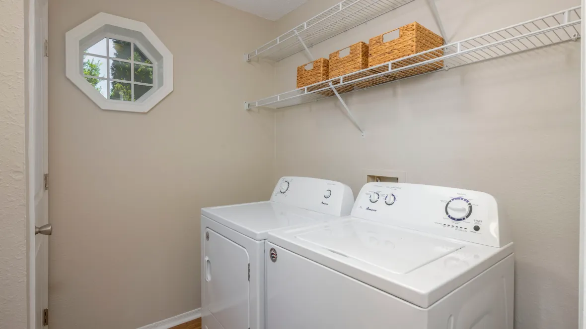 A generously-sized laundry area with full-size appliances, ample storage, and a stunning octagon-shaped window providing abundant natural light.