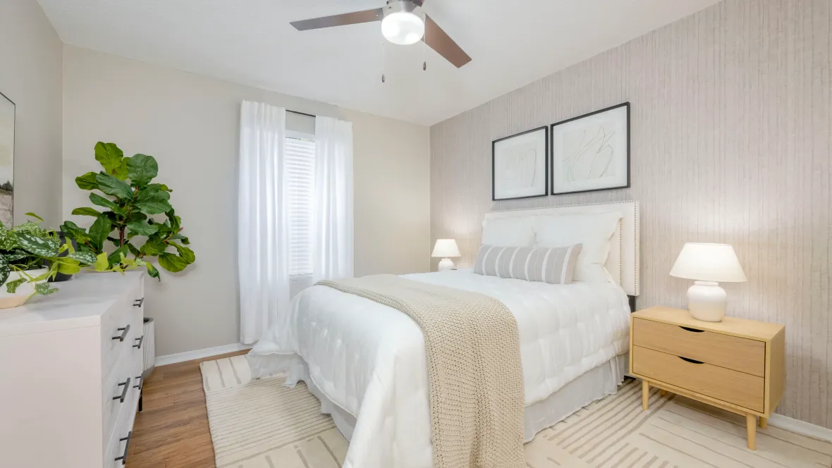 A delightful master bedroom graced with wood-style floors, a contemporary ceiling fan, and a welcoming ensuite bathroom.