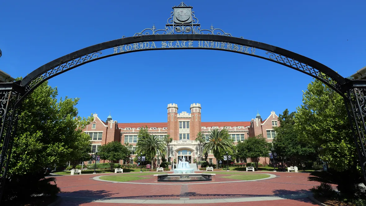 A view of the FSU campus through a historic entry arch towards the iconic Wescott Square and Fountain.