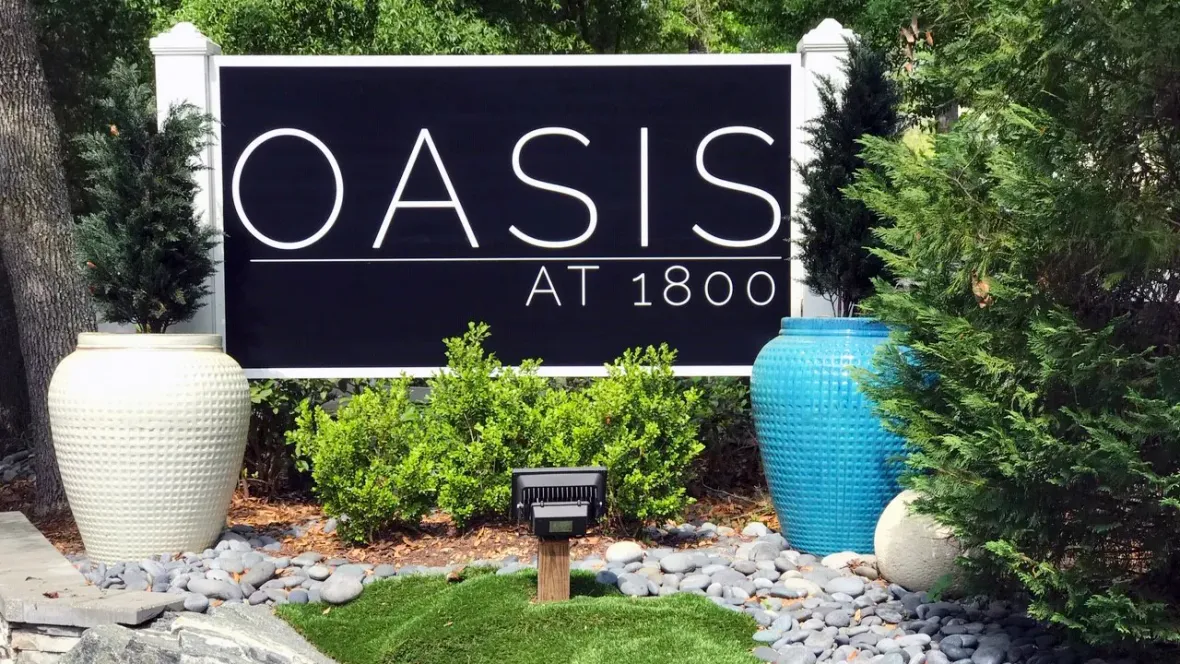 The grand gateway to Oasis at 1800, marked by a striking monument sign, enveloped by vibrant landscapes.