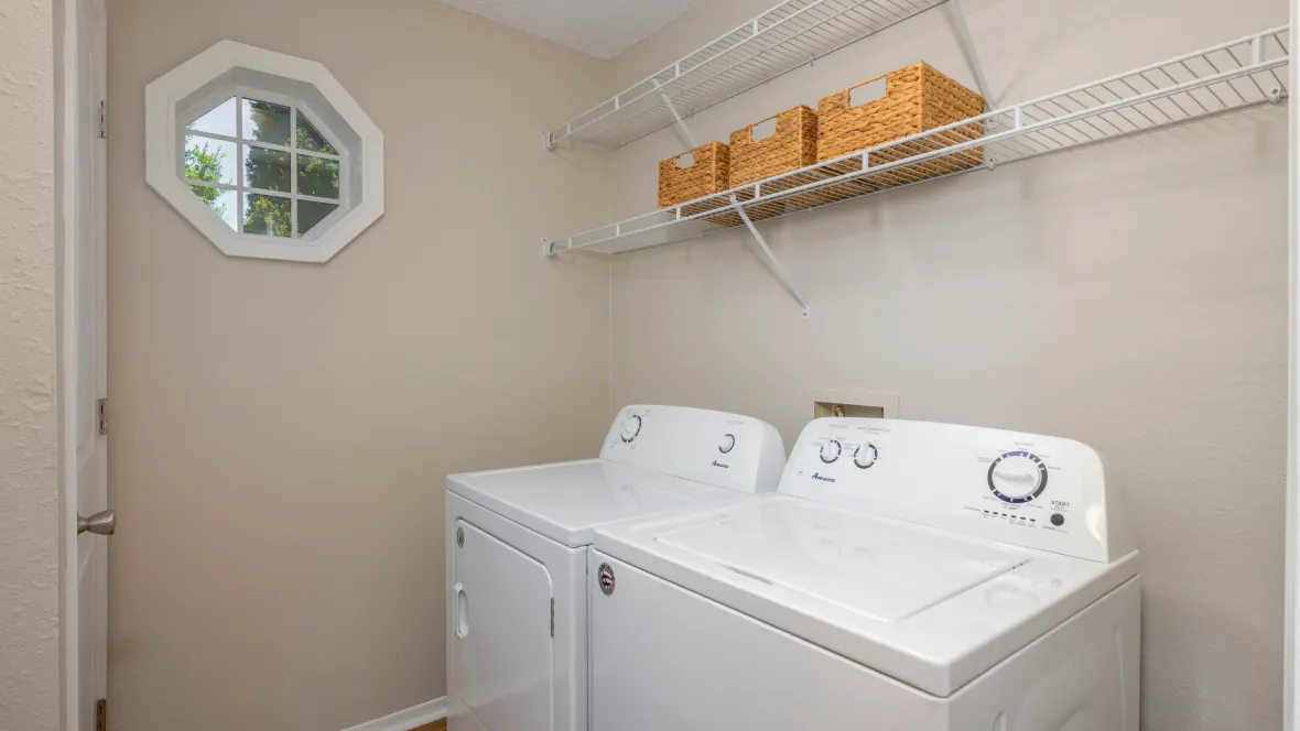 A capacious laundry area with full-size appliances, ample storage, and a charming octagon-shaped window.