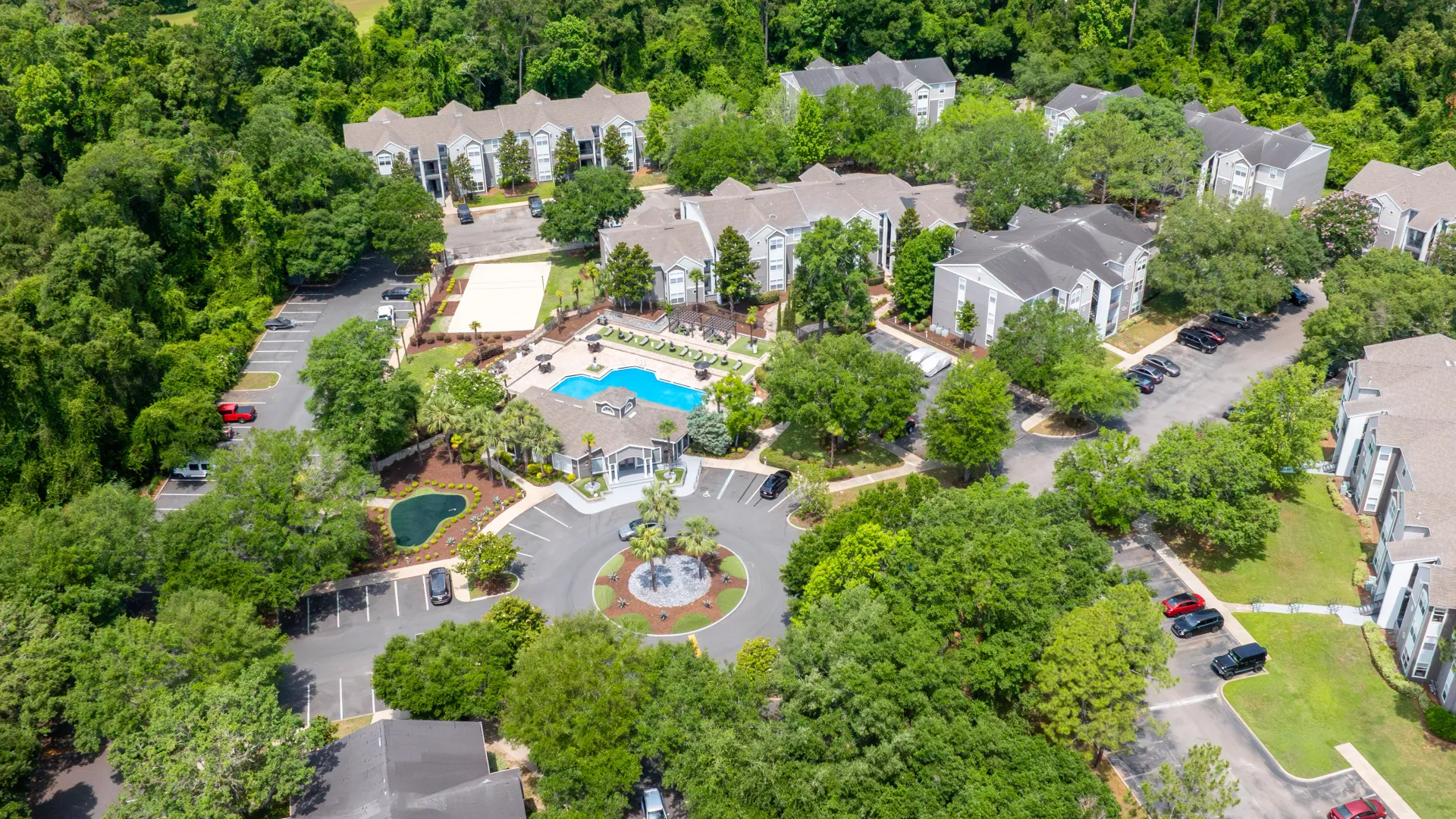 Aerial view of Oasis at 1800 apartment community with pool, clubhouse, and tree-lined surroundings.