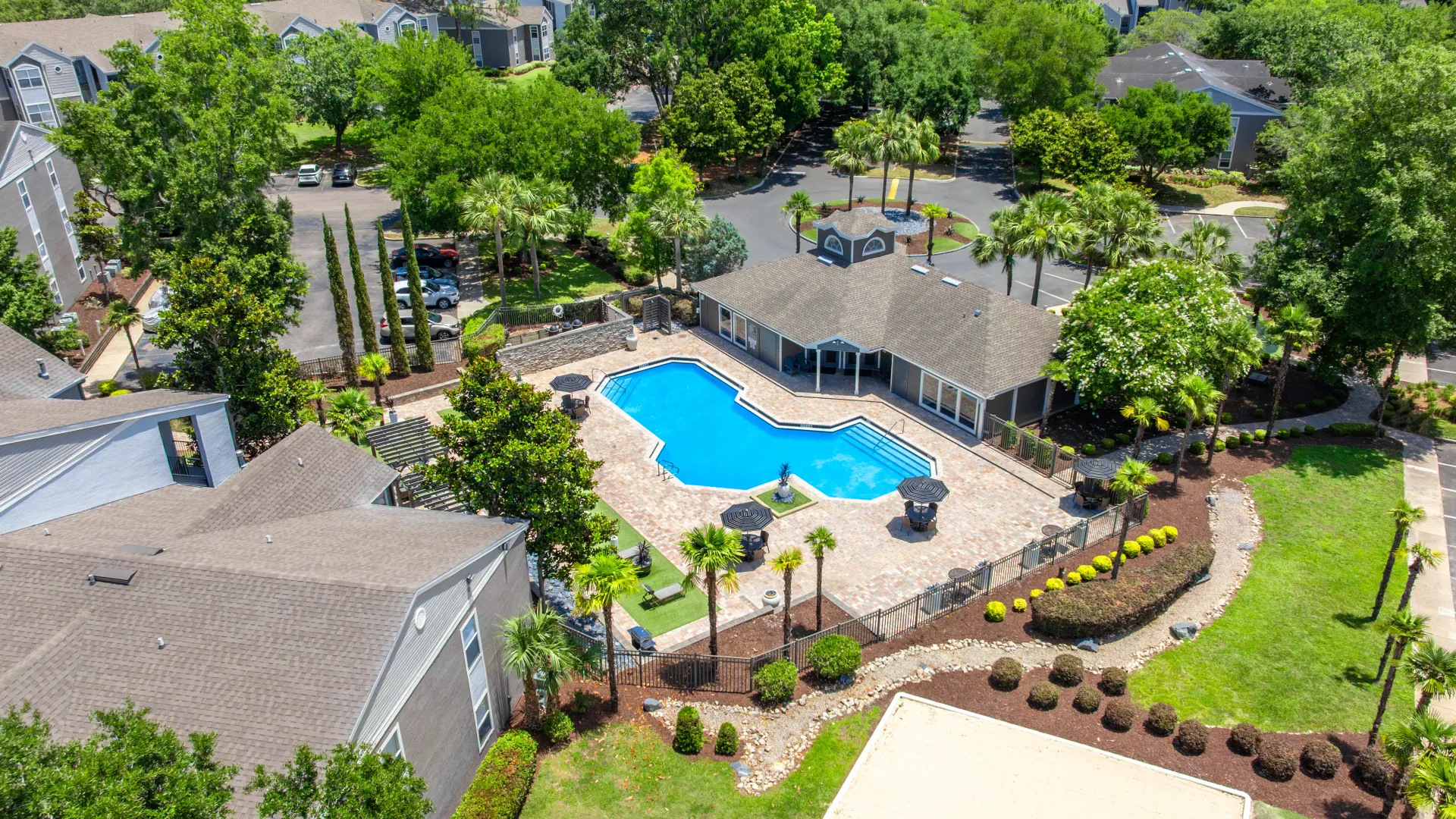 Overhead view of Oasis at 1800’s pool area with lounge chairs, umbrellas, and surrounding greenery.