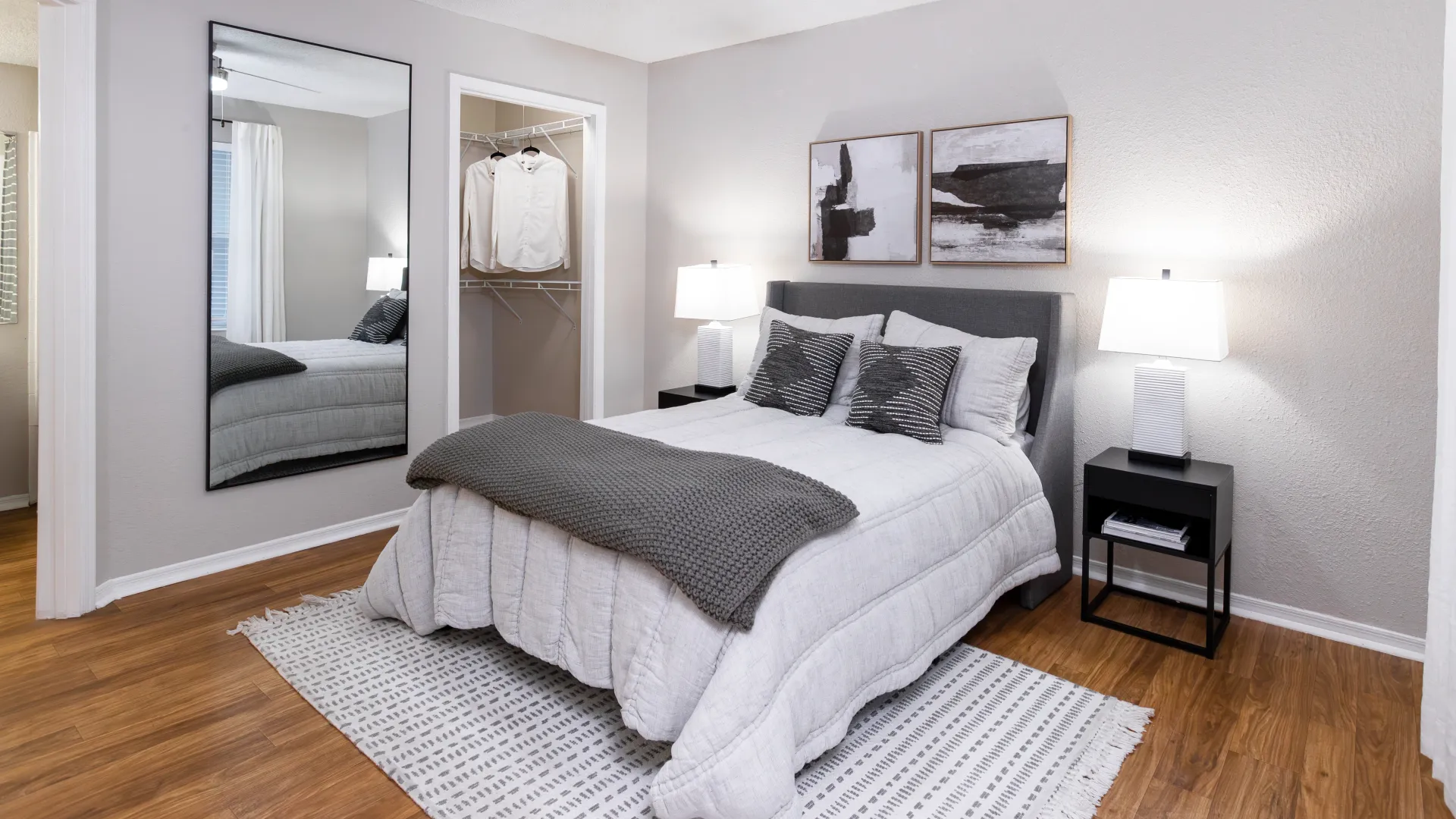 Bedroom at Oasis at 1800 with neutral décor, large mirror, open closet, and modern furnishings.