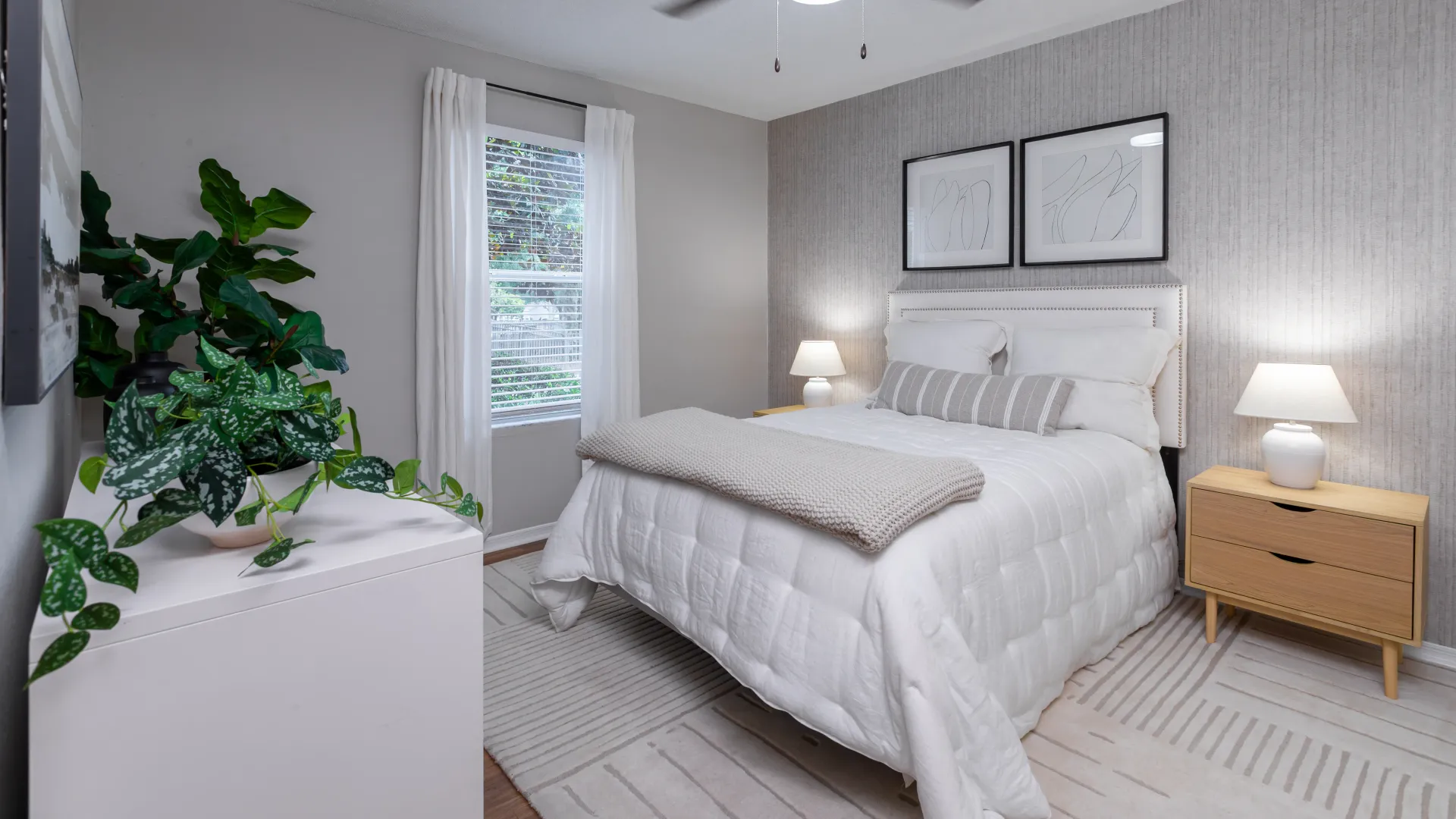 Light-filled bedroom at Oasis at 1800 with modern furnishings, textured accent wall, and minimal decor.