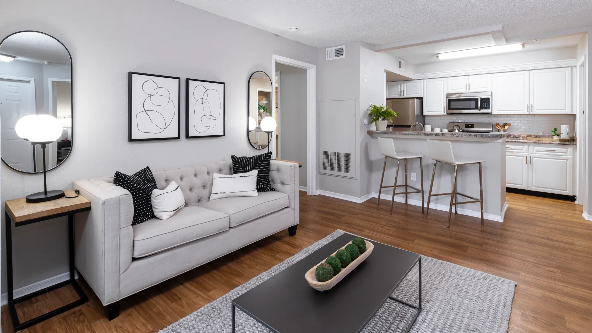 Open living room at Oasis at 1800 with wood-style floors and view into modern kitchen.