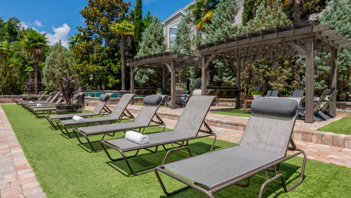 An array of poolside loungers and charming Adirondack seats beneath inviting pergolas, creating a serene haven.