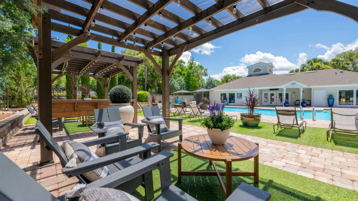 Pergola featuring Adirondack chairs, faux grass underfoot, an atmosphere of opulence, overlooking the inviting pool.