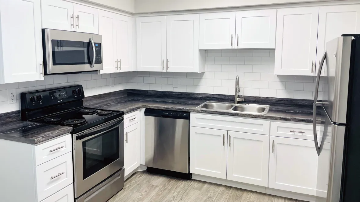 Shiny stainless-steel appliances and reflective white tiles perfectly matched to white cabinetry glistening in the natural light, infusing a hint of contemporary charm into your kitchen.