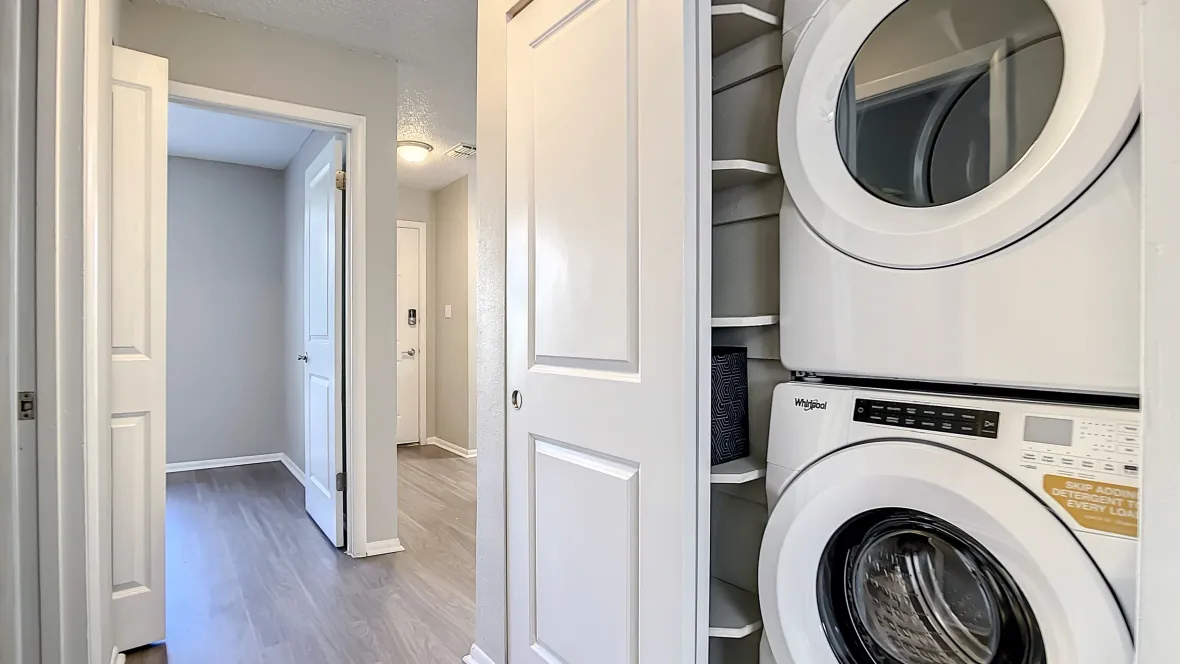Sliding doors reveal a laundry room conveniently located in the hallway – complete with stackable appliances and an adjoining linen closest. 