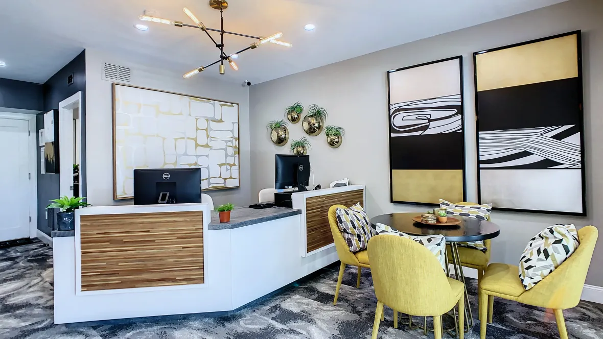 A beautifully designed leasing center with a stunning central desk where our friendly team eagerly awaits and a cozy table and chairs offering a space to relax. 