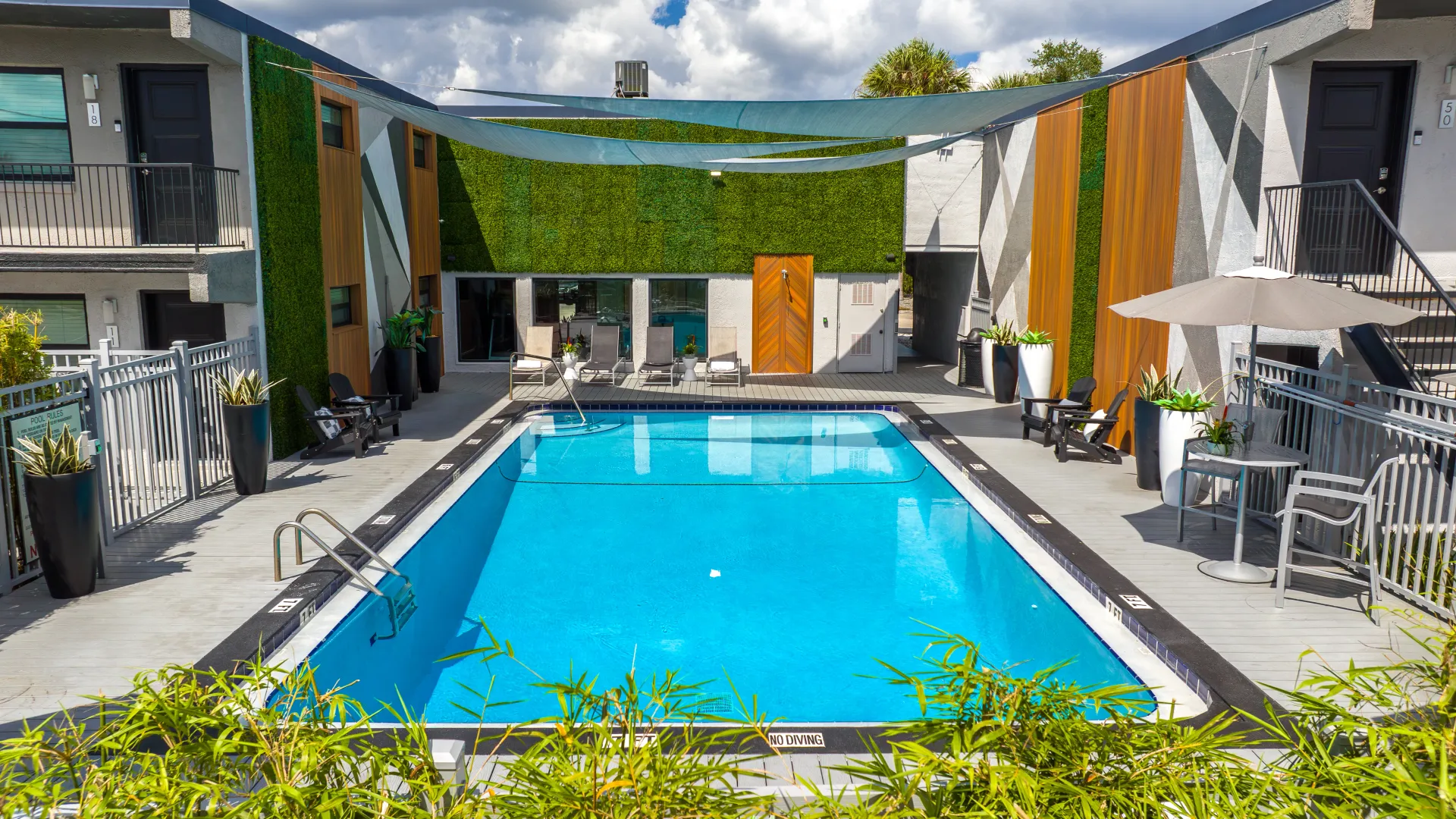 Elon Winter Park pool area with modern lounge chairs, vibrant greenery, and shaded seating, offering a serene and stylish environment for relaxation and recreation.