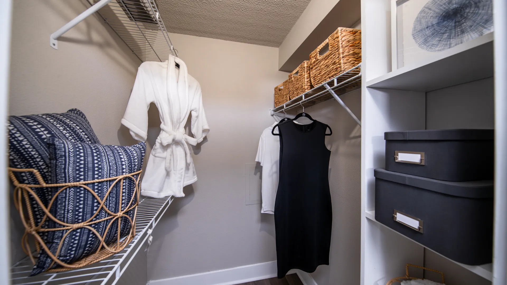 Walk-in closet featuring wire shelving, storage baskets, hanging clothes, and organized storage boxes.