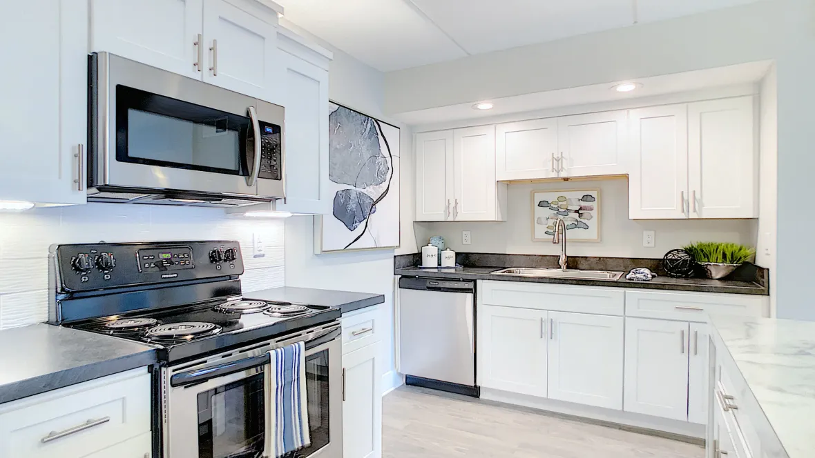 A view of both walls of the kitchen, lined with ample white cabinetry and stainless steel appliances.