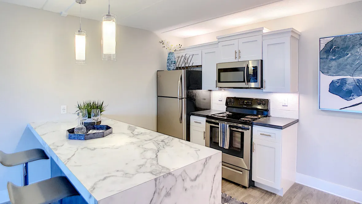 A corner of the kitchen featuring the Carrara marble inspired breakfast bar, stainless steel refrigerator, stove, and built-in microwave.