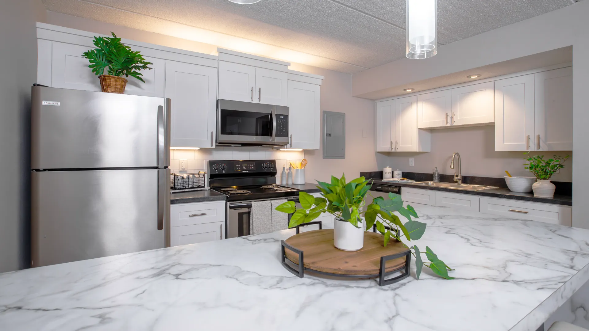 Modern kitchen with stainless steel appliances, white cabinetry, and a marble countertop at Elon Winter Park Apartments.