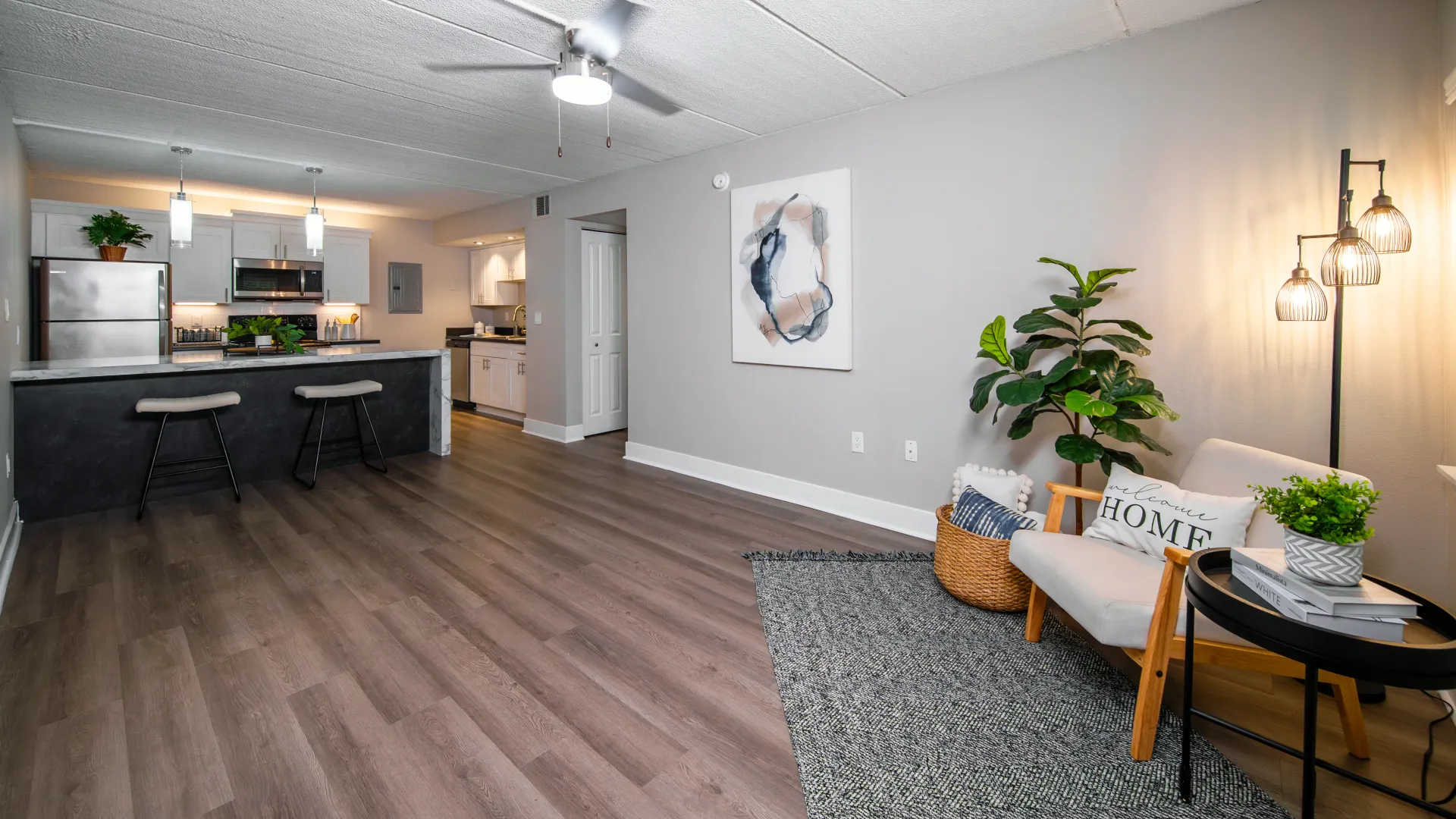 Open-concept kitchen and living room with stainless steel appliances, bar seating, modern artwork, and a cozy seating area at Elon Winter Park Apartments.