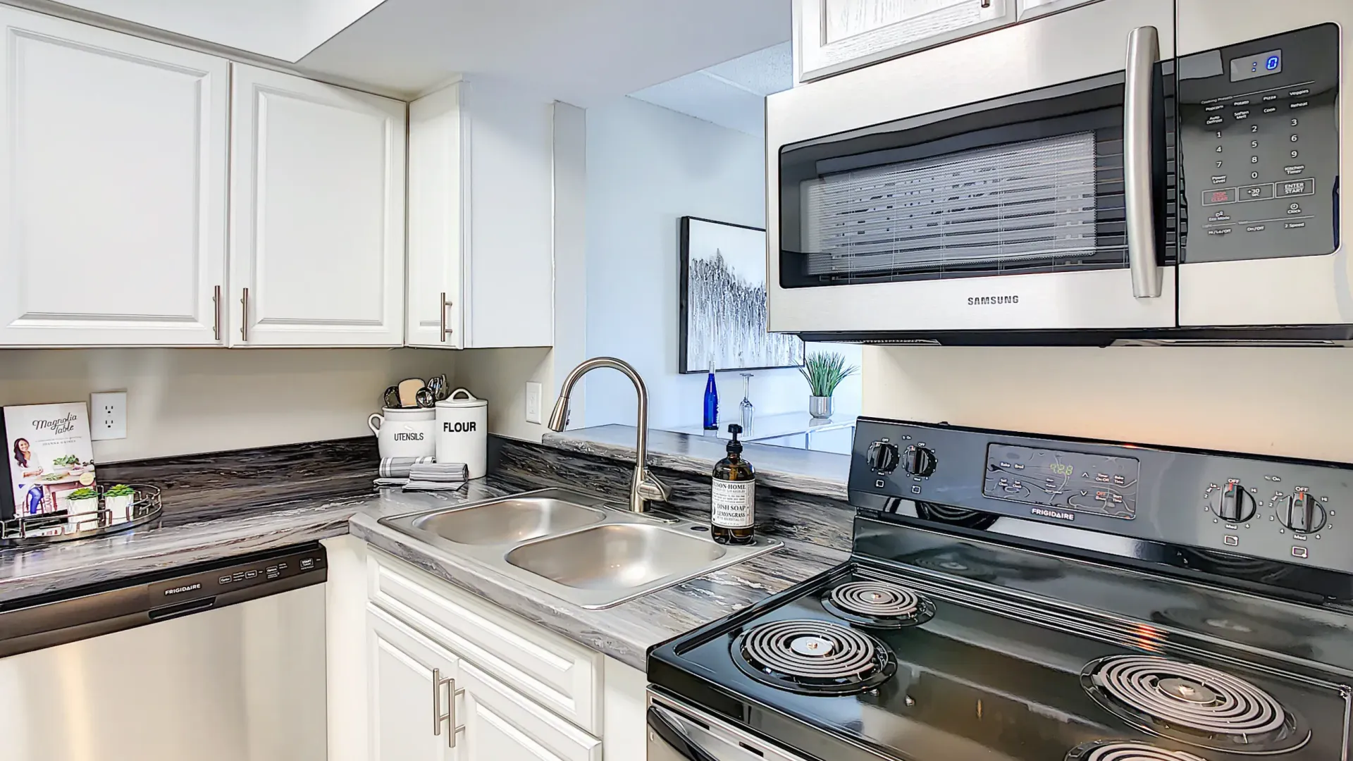 A well-appointed kitchen boasting ample upper and lower cabinets for optimized storage, highlighted by stainless steel appliances, including a microwave above the stove.