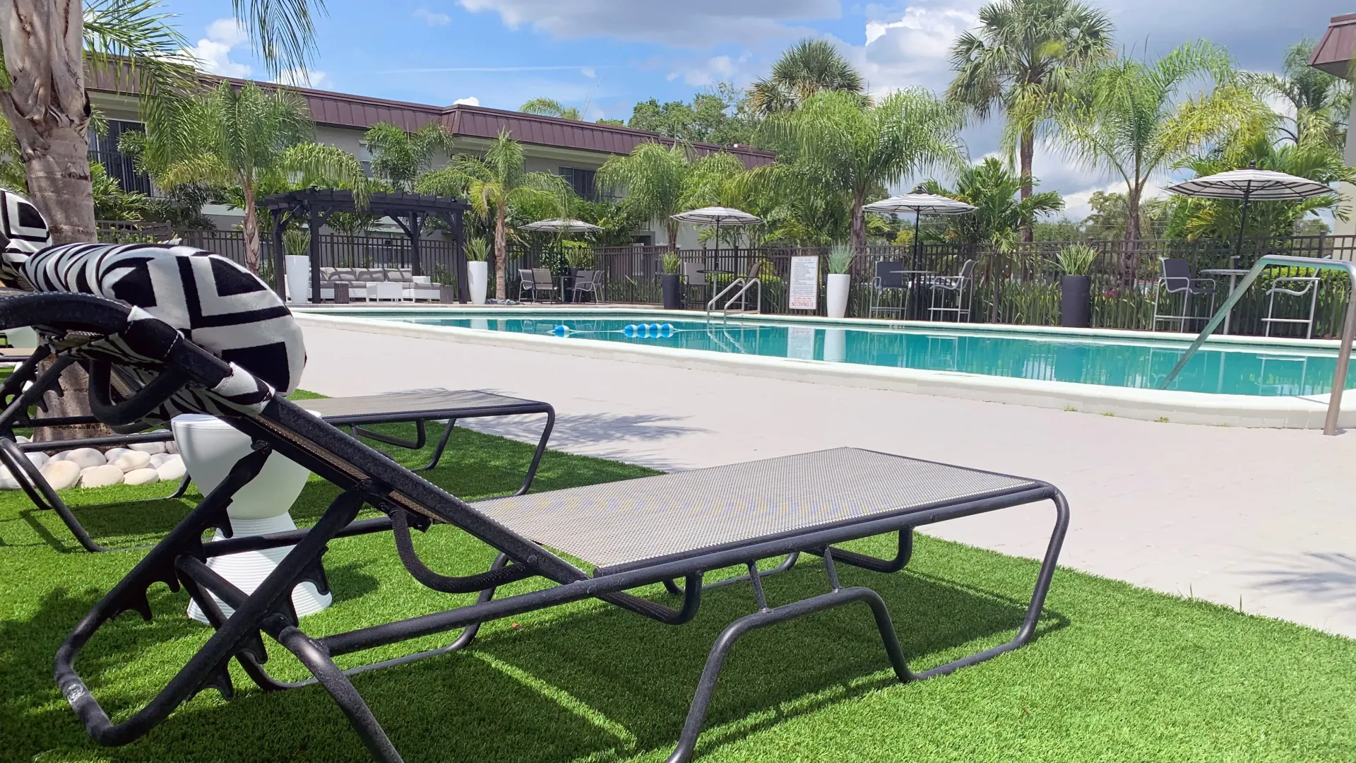 A glistening pool with comfortable seating options around the pool deck, conveniently positioned near apartment buildings.