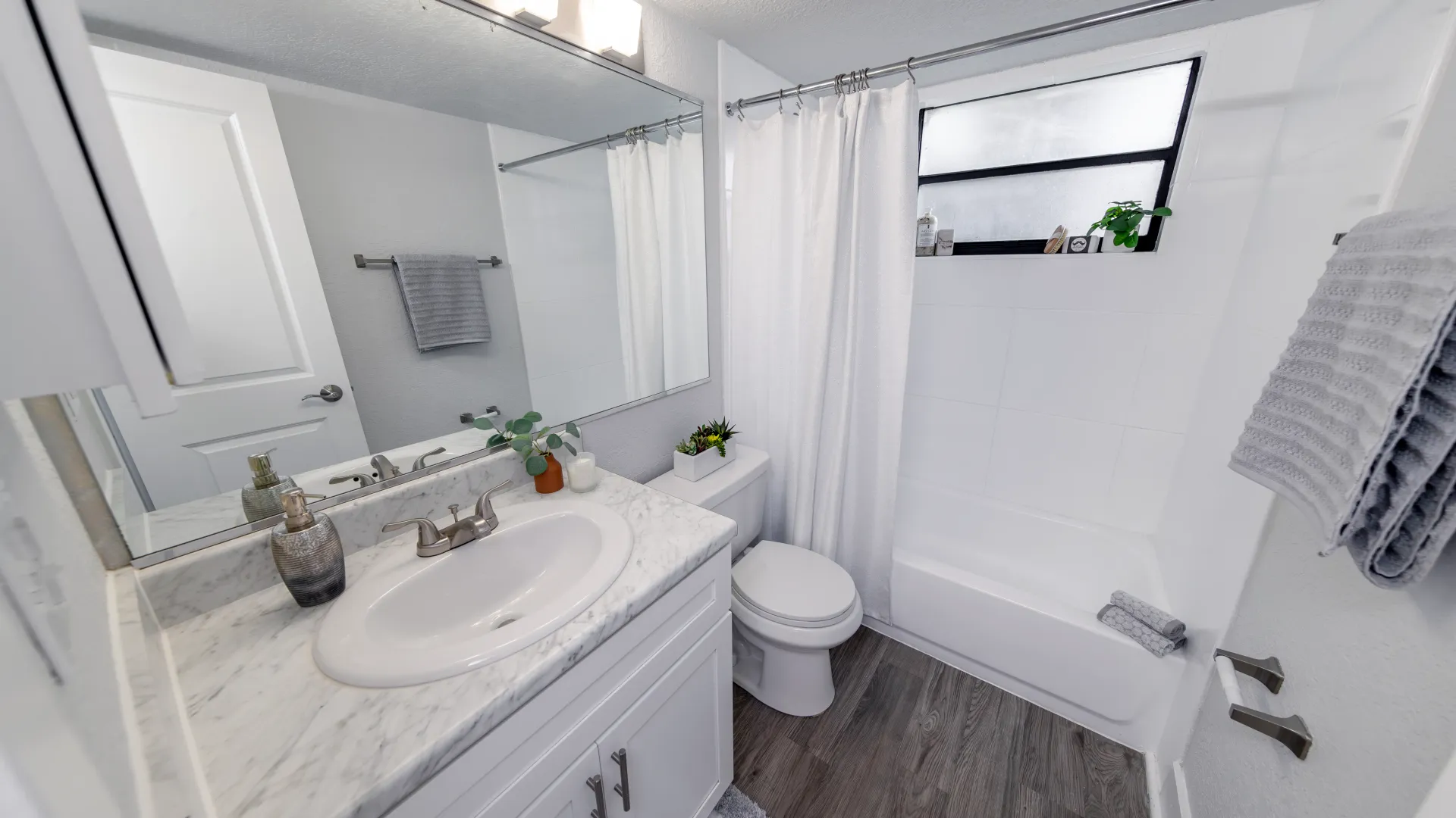 Modern bathroom at Poste Winter Park apartment featuring a marble-style vanity, clean white shower, and stylish fixtures.