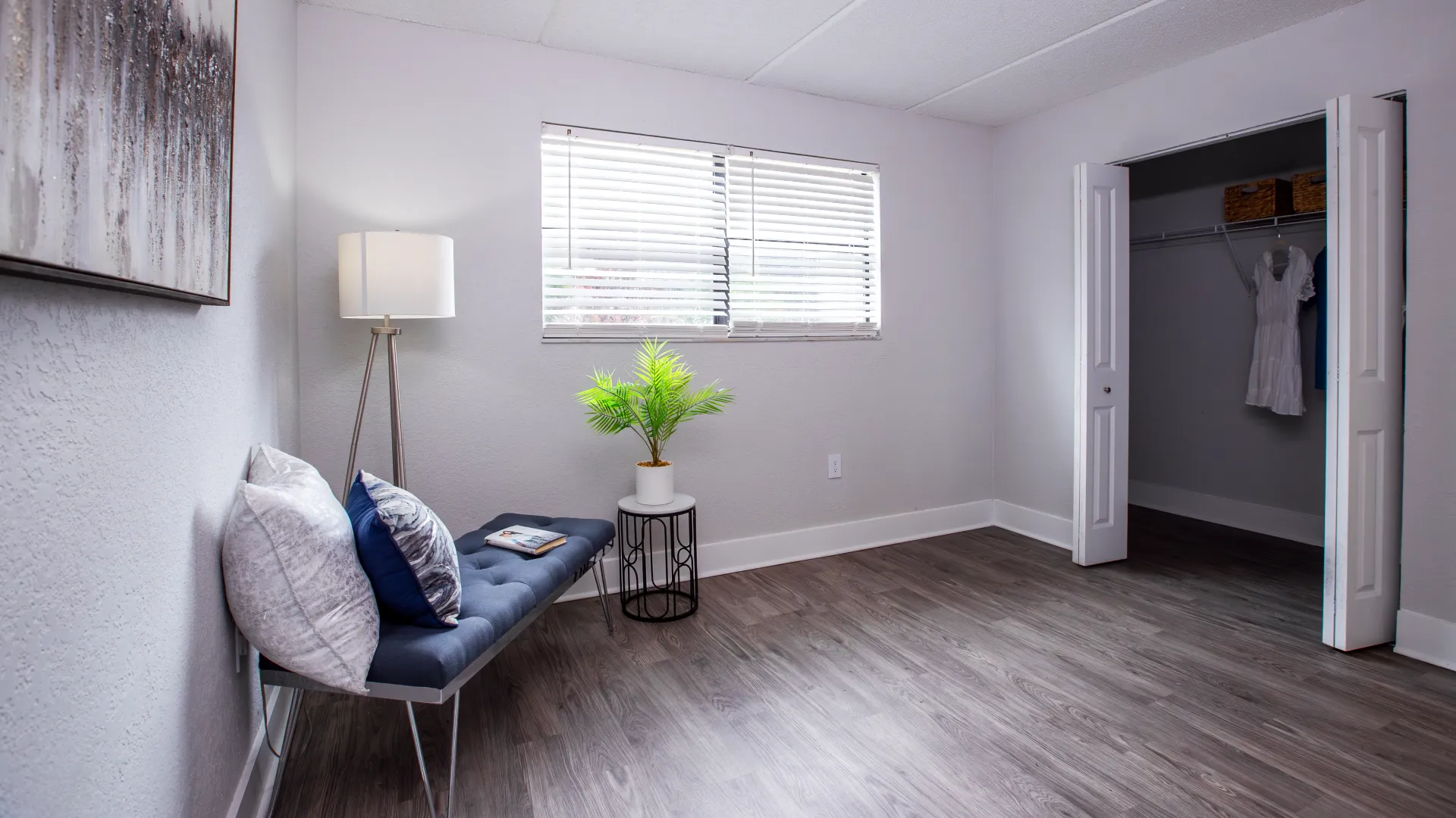 Spacious bedroom in an apartment at Poste Winter Park, featuring a large window, wood-style flooring, and a closet with double doors.