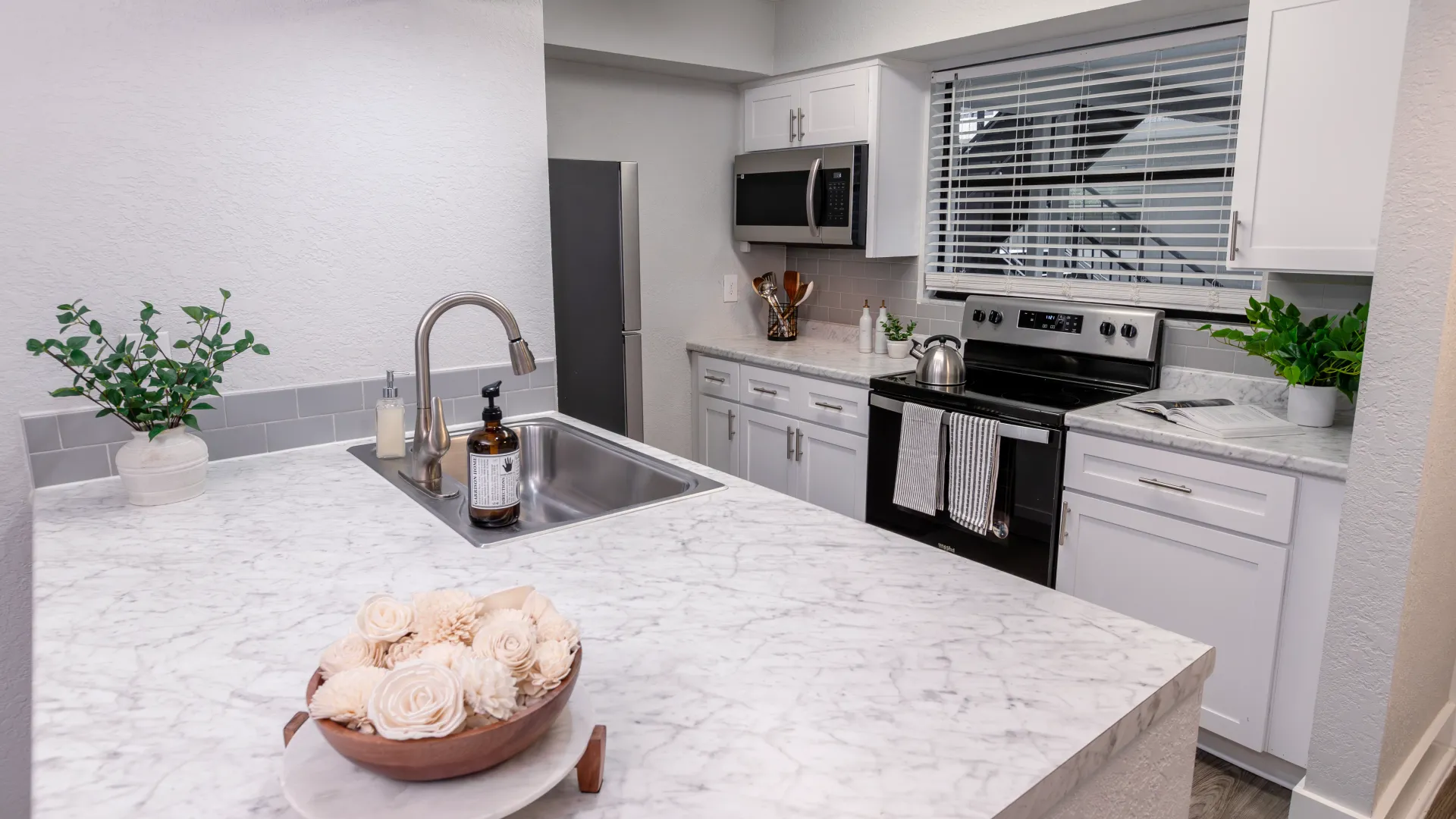 Contemporary kitchen featuring marble-style countertops, stainless-steel appliances, and sleek cabinetry.