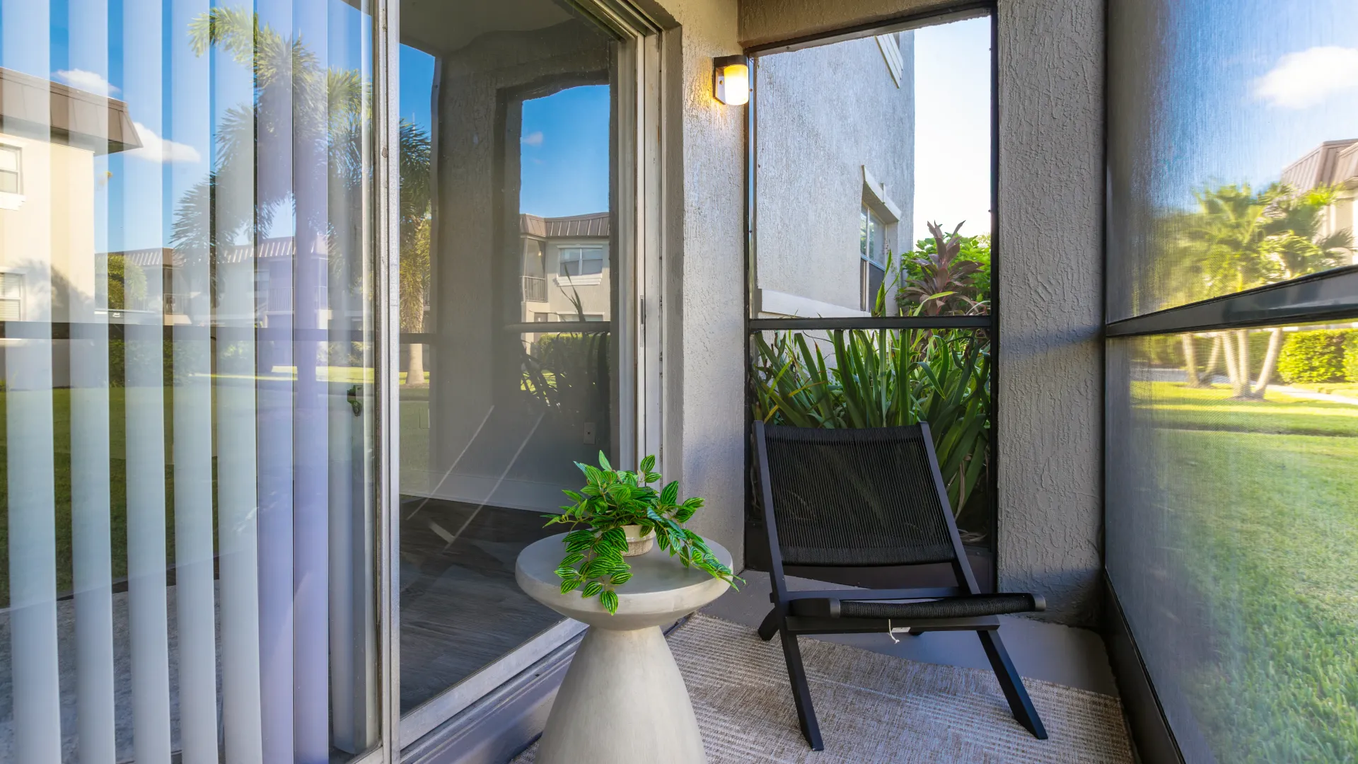 Private screened patio at Poste Winter Park featuring a chair, small table with a plant, and views of a garden area.