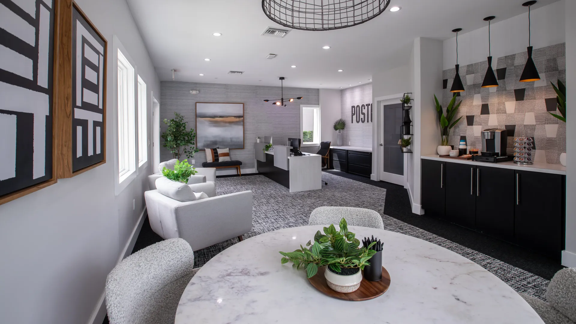 Modern leasing office at Poste Winter Park Luxury Apartments featuring comfortable seating, contemporary décor, and a refreshment station for residents and visitors.