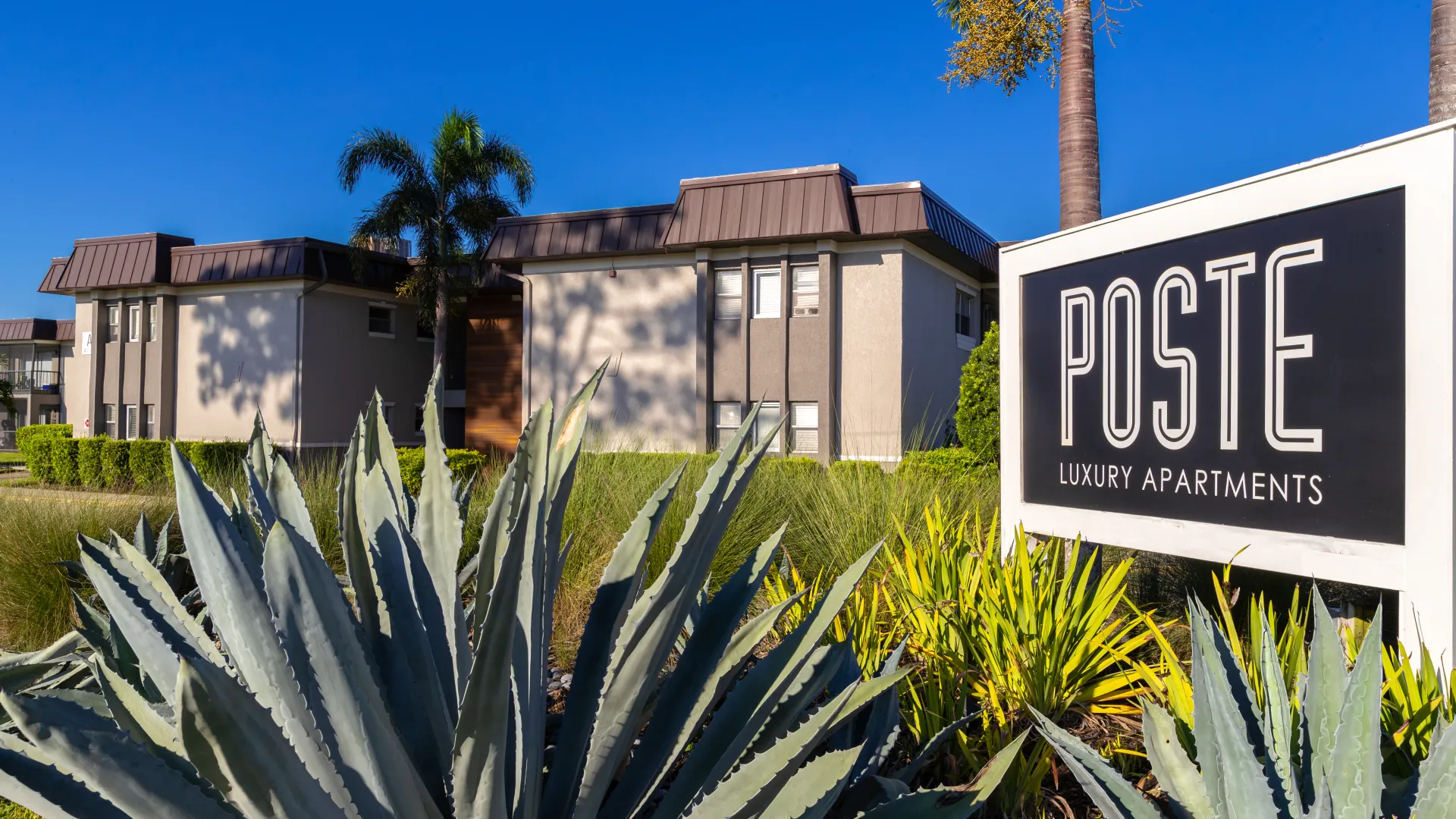 Poste Luxury Apartments sign with modern building exteriors and lush landscaping, welcoming residents to a serene and upscale living community.