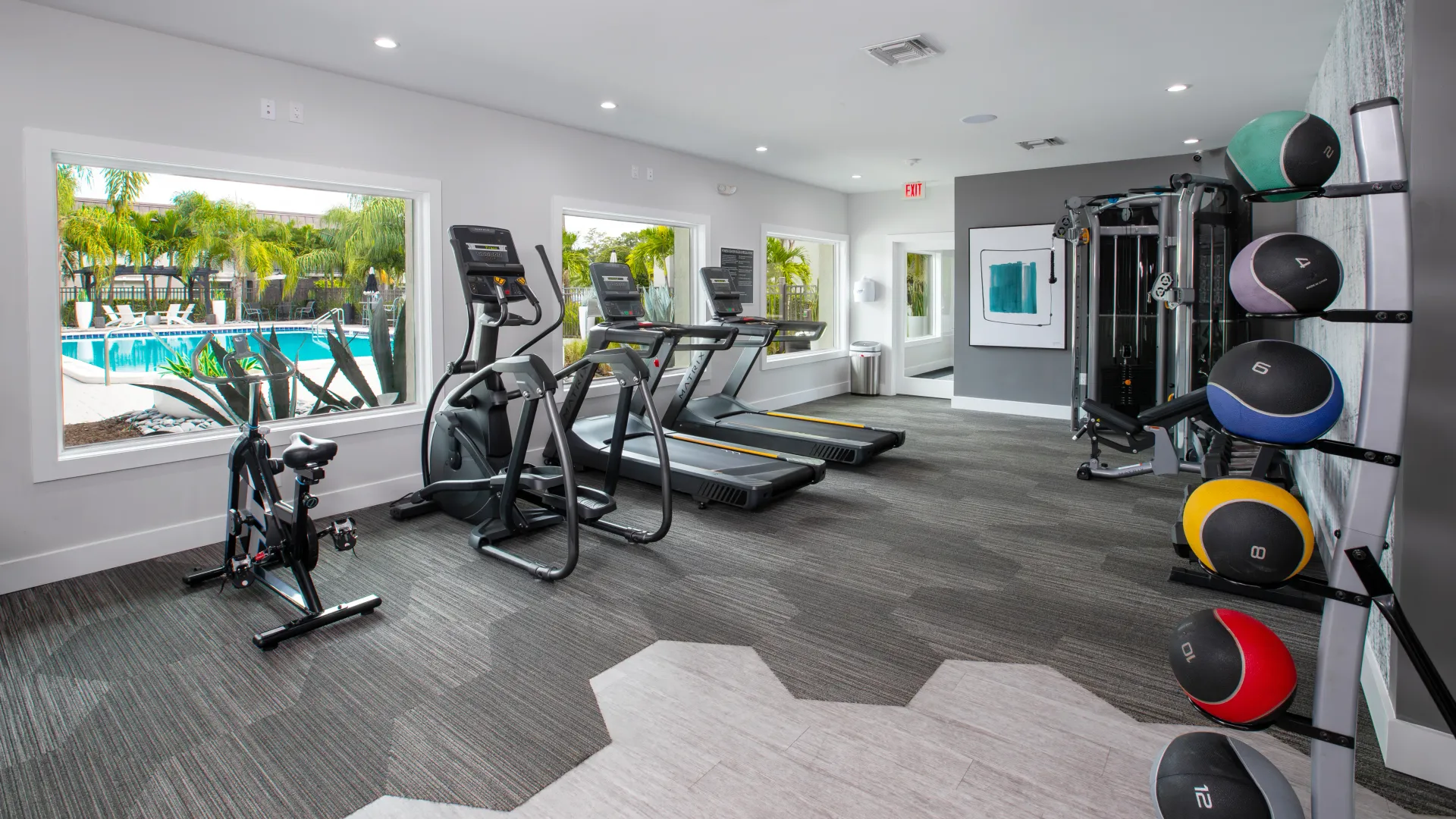 24-hour fitness center featuring treadmills, weight machines, and a stationary bike with views of the pool for a motivating workout experience.