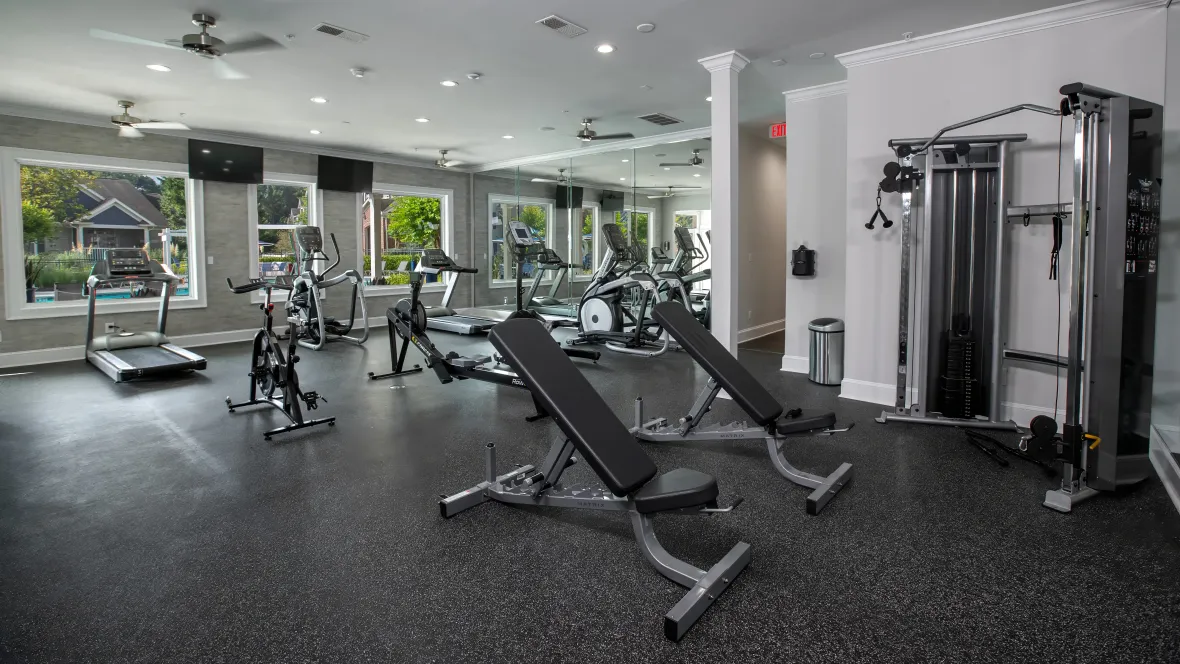 A section of the fitness center showcasing a range of weight training equipment – including a total-body workout system and weight benches – inviting residents to engage in strength-building exercises.