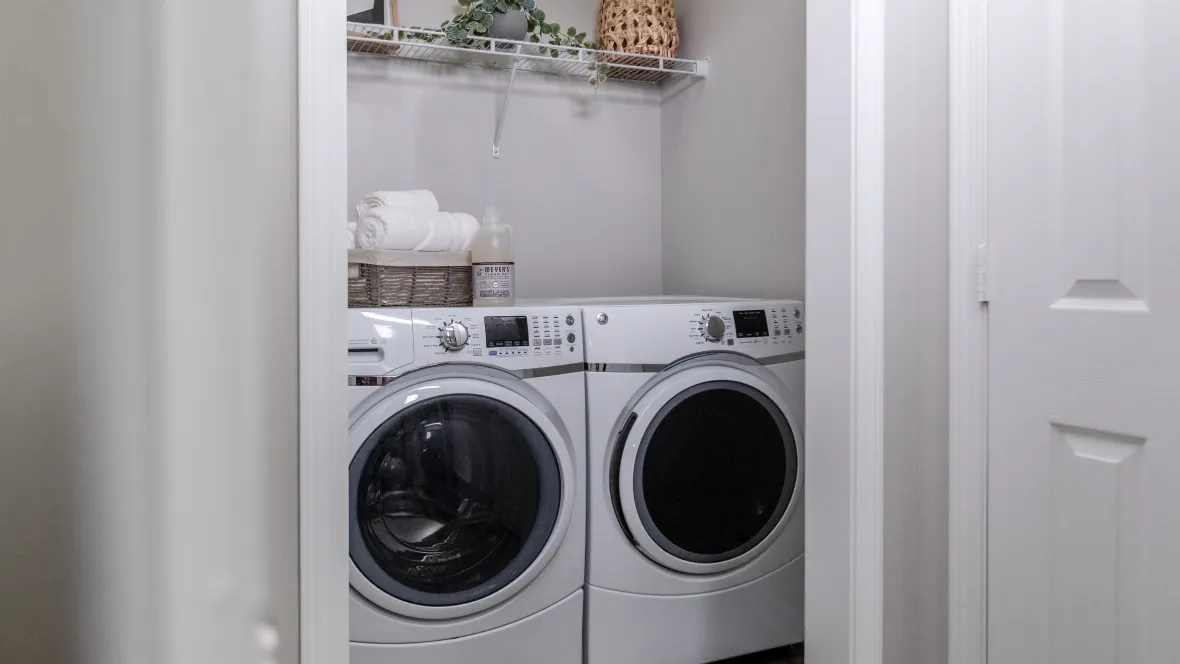 Large front-loading washer and dryer set in a roomy laundry room just off the kitchen, offering residents ease and efficiency in managing laundry tasks at The Everlee.