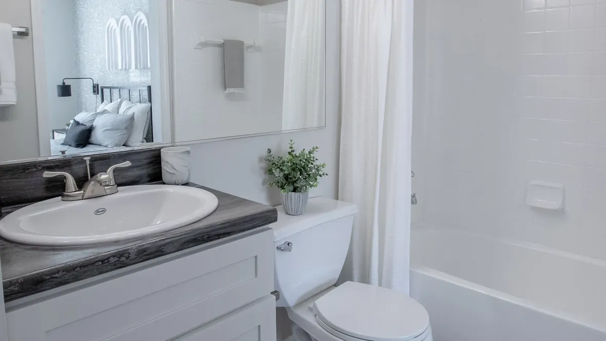 A large, extended bathroom mirror with upgraded, modern vanity lighting